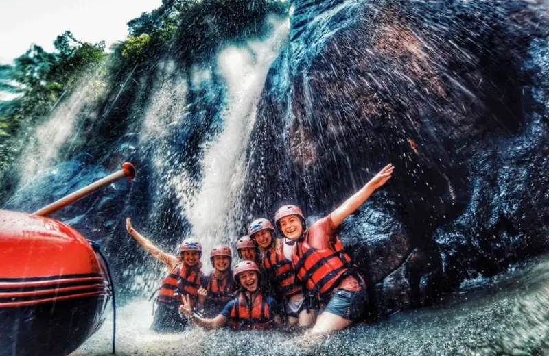 Group cheering by a jungle waterfall on the river